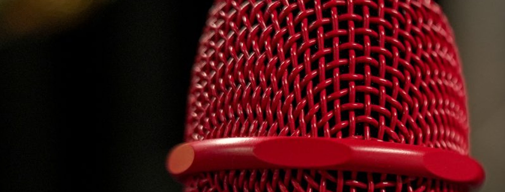 The grille of a red dynamic microphone, filling the frame
