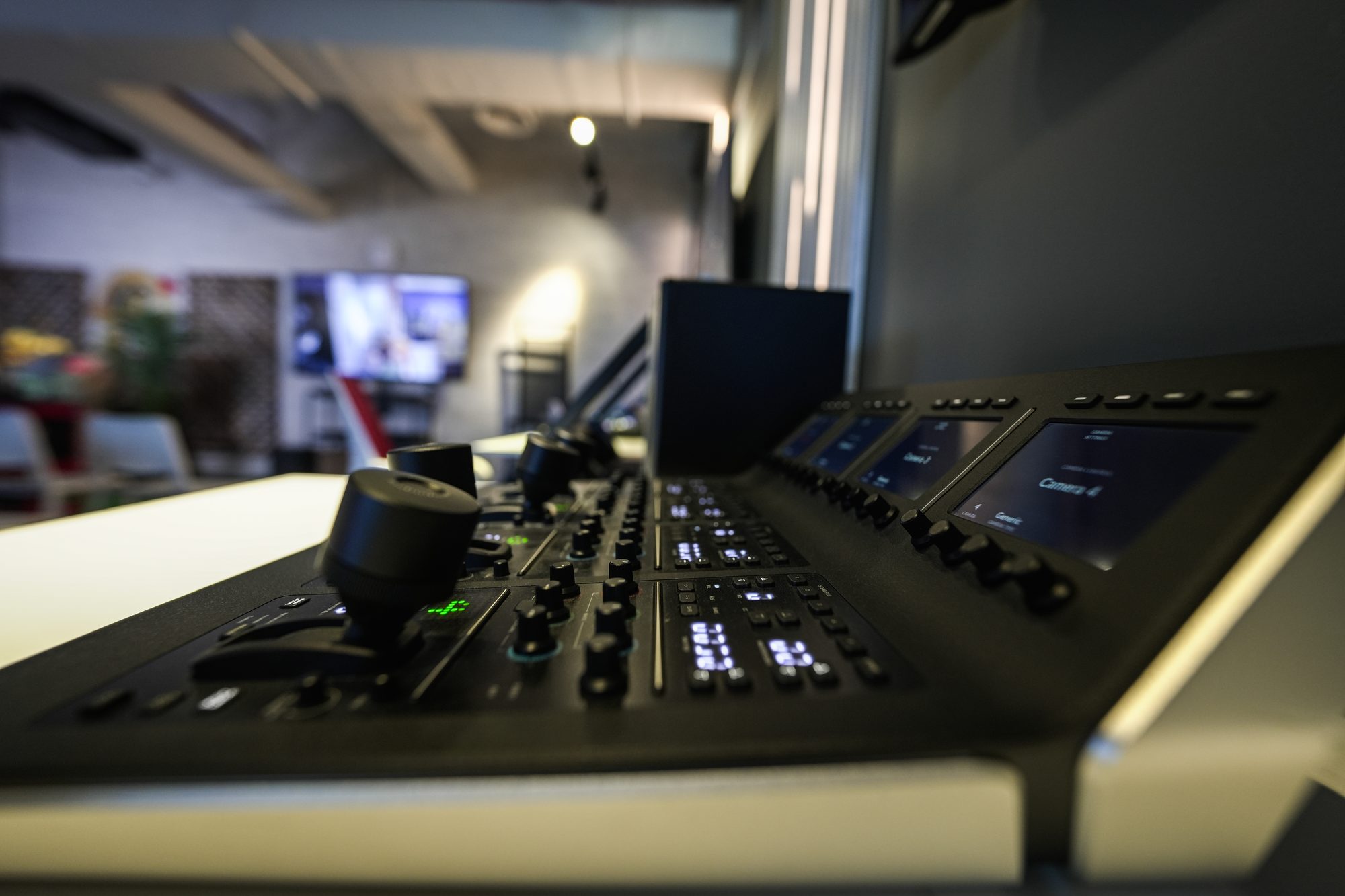 A camera control panel at MCX, joystick and channel displays lit, the gallery beyond it out of focus