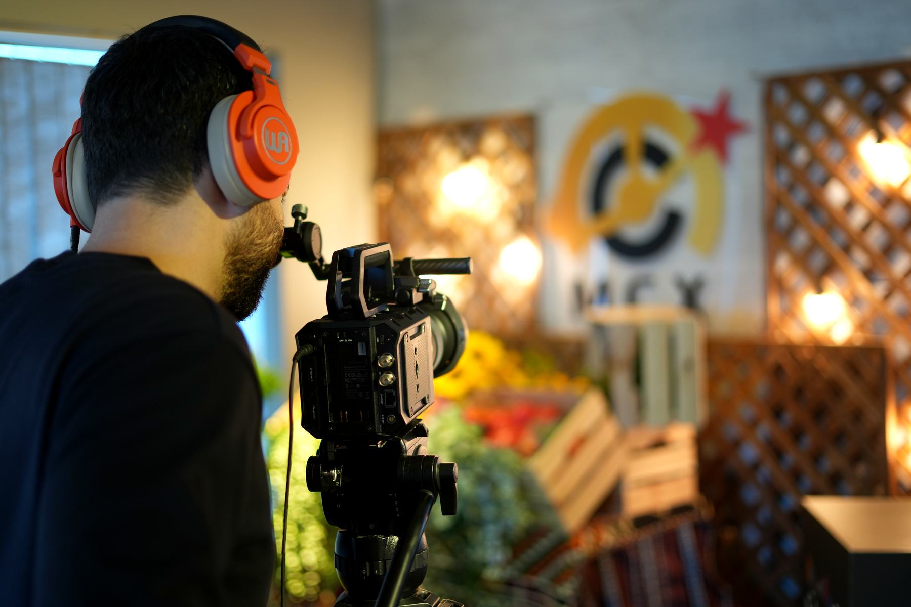 An operator behind a camera on the MCX floor, headphones on